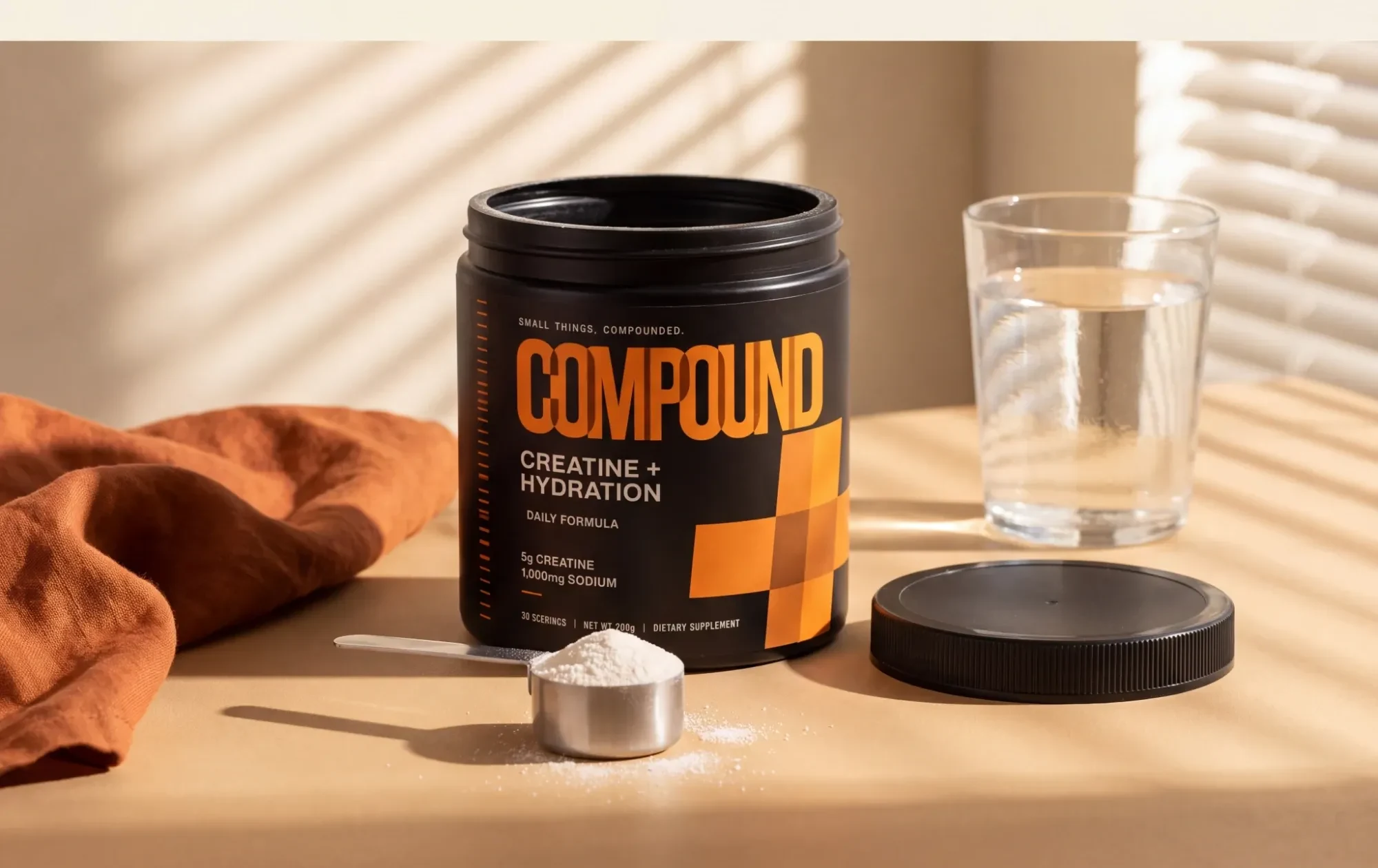 A tub of Compound on a kitchen counter beside a filled scoop and a glass of water